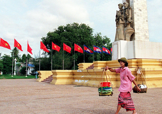 a-cambodian-woman-selling-food-walks-past-the-vietnamese-cambodian-friendship-monument