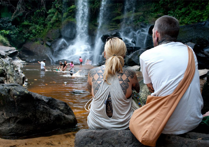 a-couple-sits-on-the-rock-in-front-of-the-waterfall-at-kulen-mountain