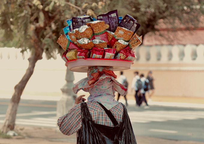 a-woman-walking-on-the-street-with-snacks-on-her-head