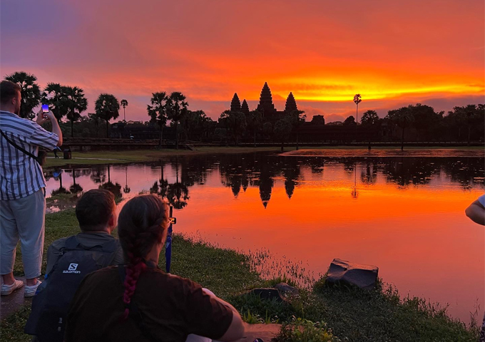 visitors-holding-cameras-sitting-on-the-lawn-to-see-the-impressive-sunrise-at-angkor-wat